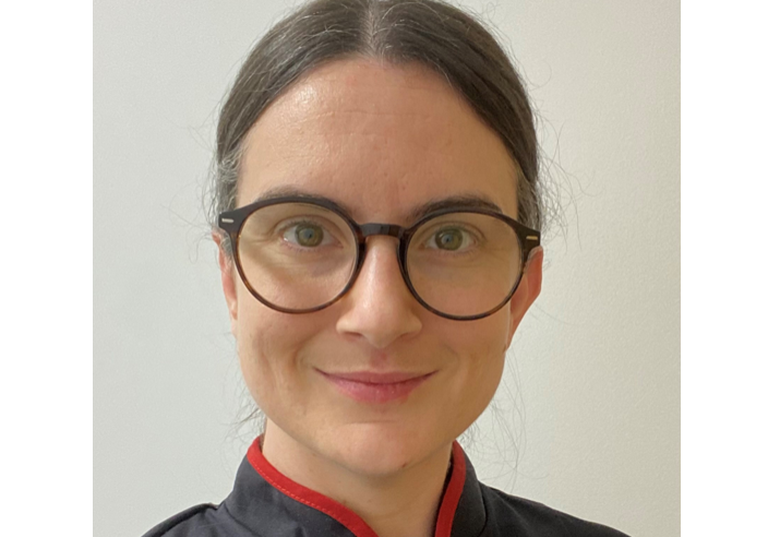Photo of white woman with tied back dark hair and dark rimmed round glasses
