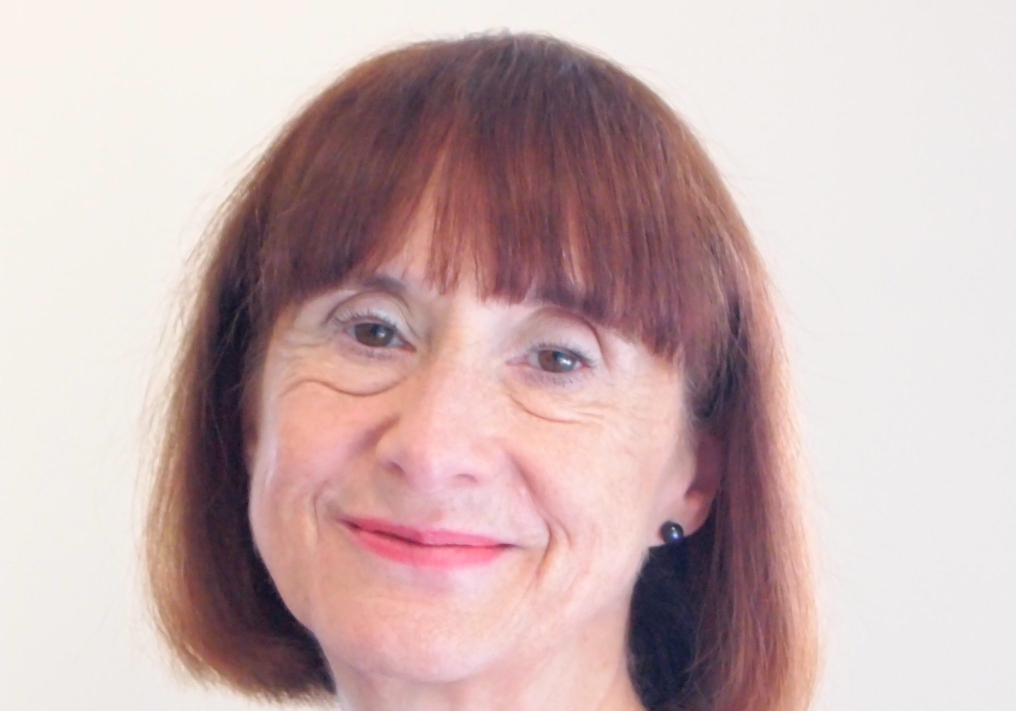 Photo of lady with dark redish bobbed hair with a fringe wearing a delicate necklace